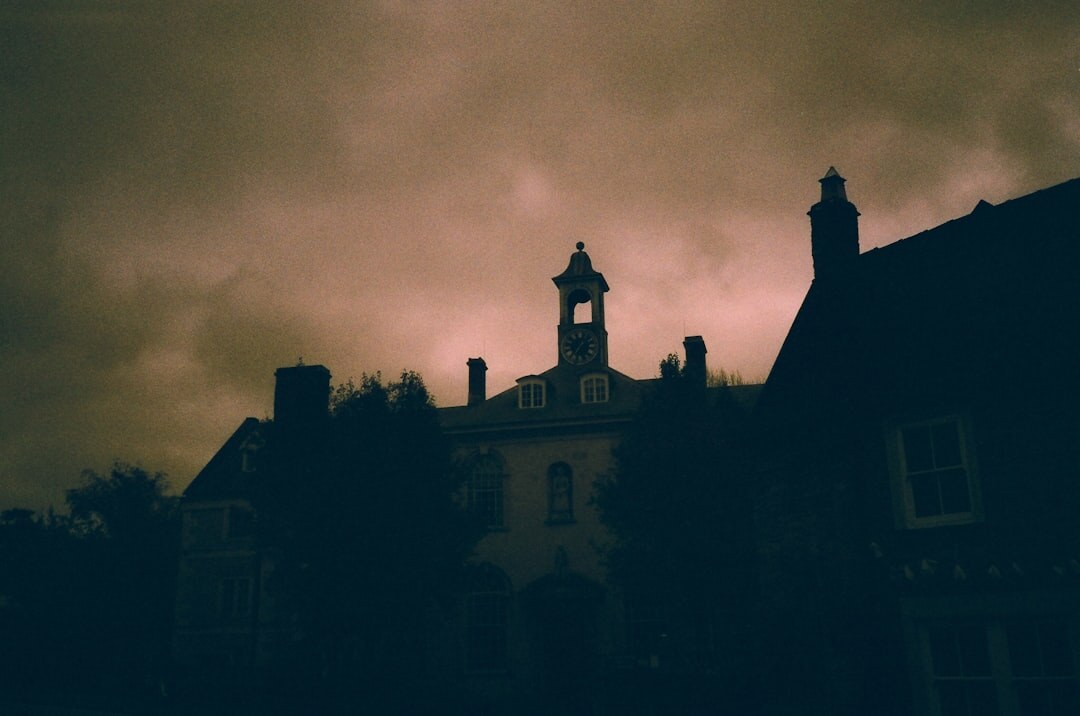 Illustrated detective book cover of an old mansion silhouette against a stormy sky