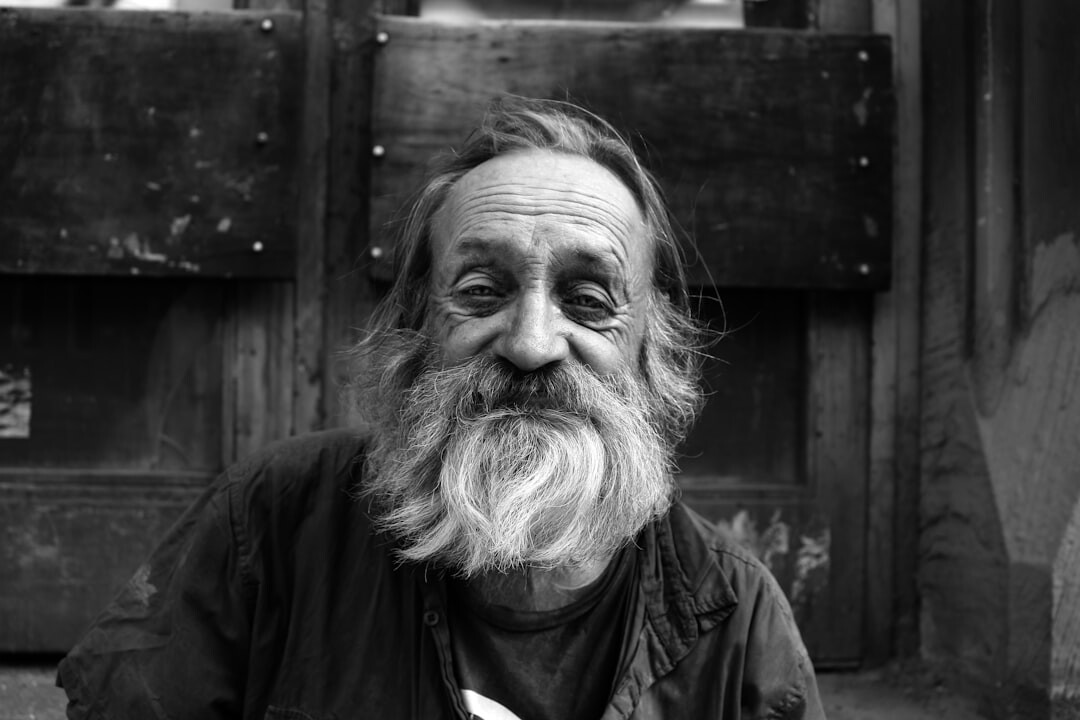 Studio portrait of an older Dutch male mystery writer with a grey beard wearing a cardigan